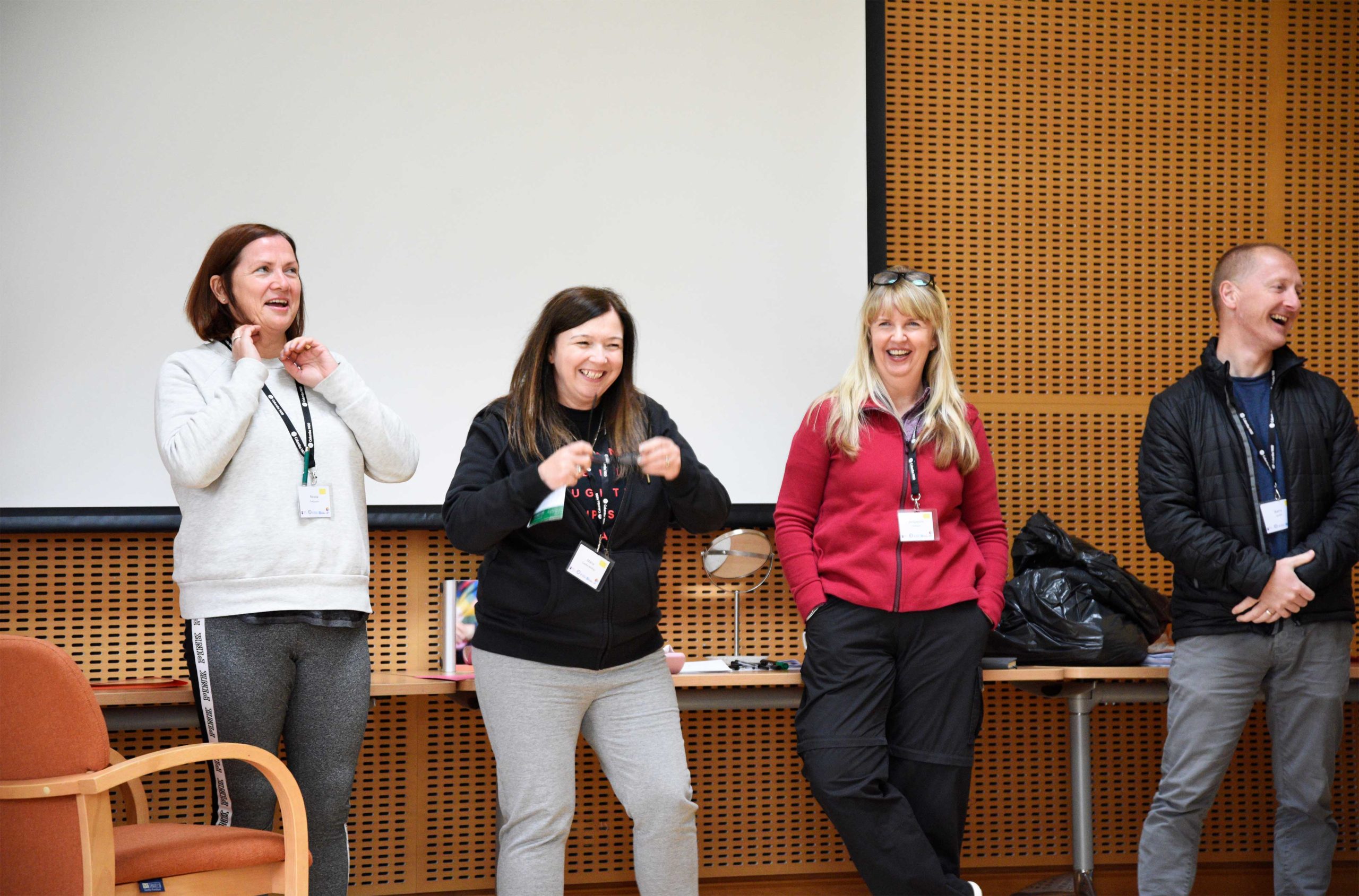 Four people laughing while giving a presentation